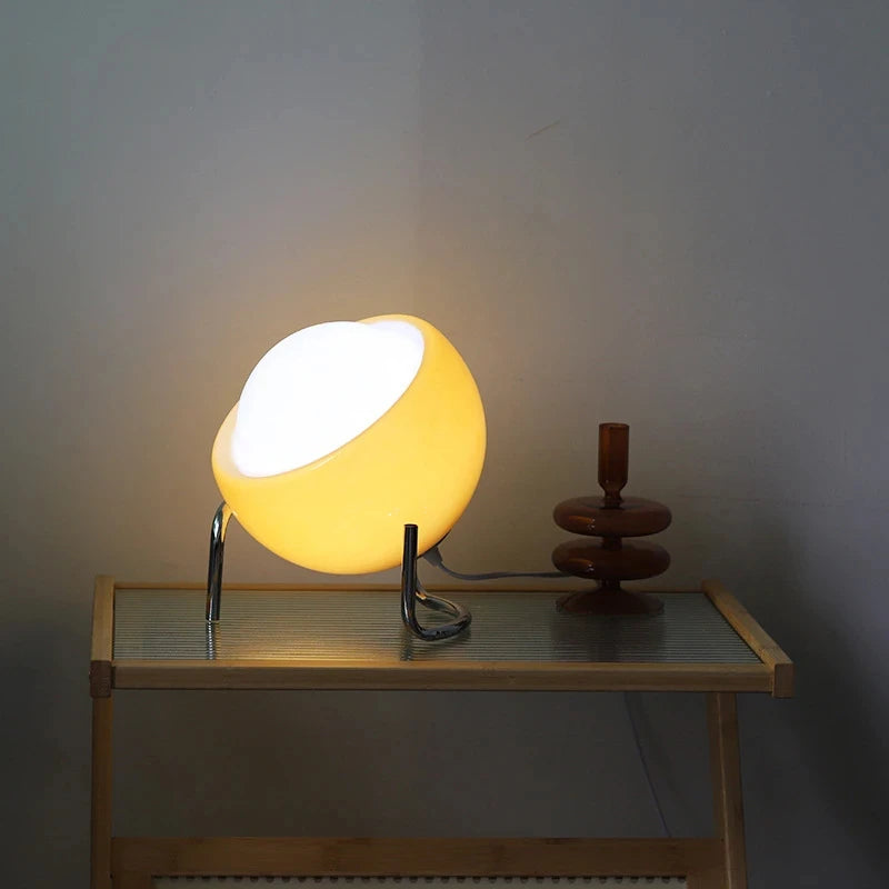 Amber glow glass table lamp with chrome base, lit globe on tabletop