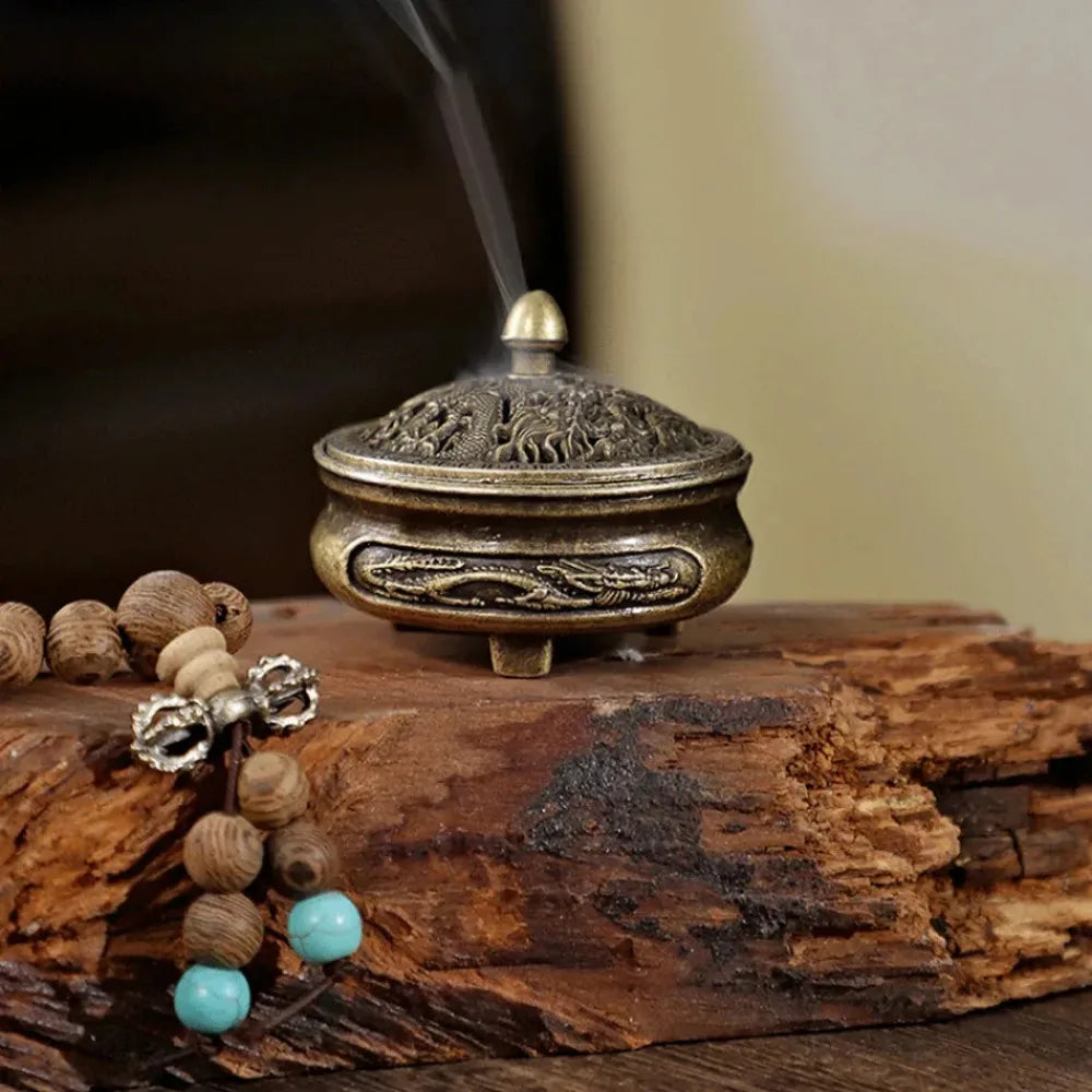 Brass engraved incense burner on wood, dragon motif on lid with incense smoke rising