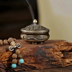 Brass engraved incense burner on wood, dragon motif on lid with incense smoke rising