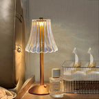 Cordless table lamp with ribbed glass shade and tall gold stand, warm light glowing