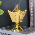 Gold metal incense holder with ornate crown shape and central finial, tabletop decor