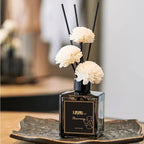 Classic reed diffuser set in dark glass bottle with black reeds and white flower heads
