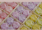 Assorted rose-shaped scented candles in gift tray, including lilac and yellow