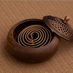 Round solid wood incense tray with spiral holder inside and lid partially shown