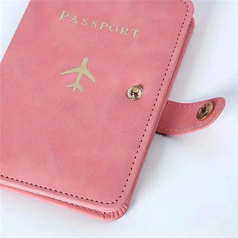 Blush pink passport cover close-up with “PASSPORT,” airplane emblem, and snap hardware