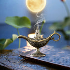 Ornate Aladdin lamp incense burner in antique brass with incense smoke rising from top