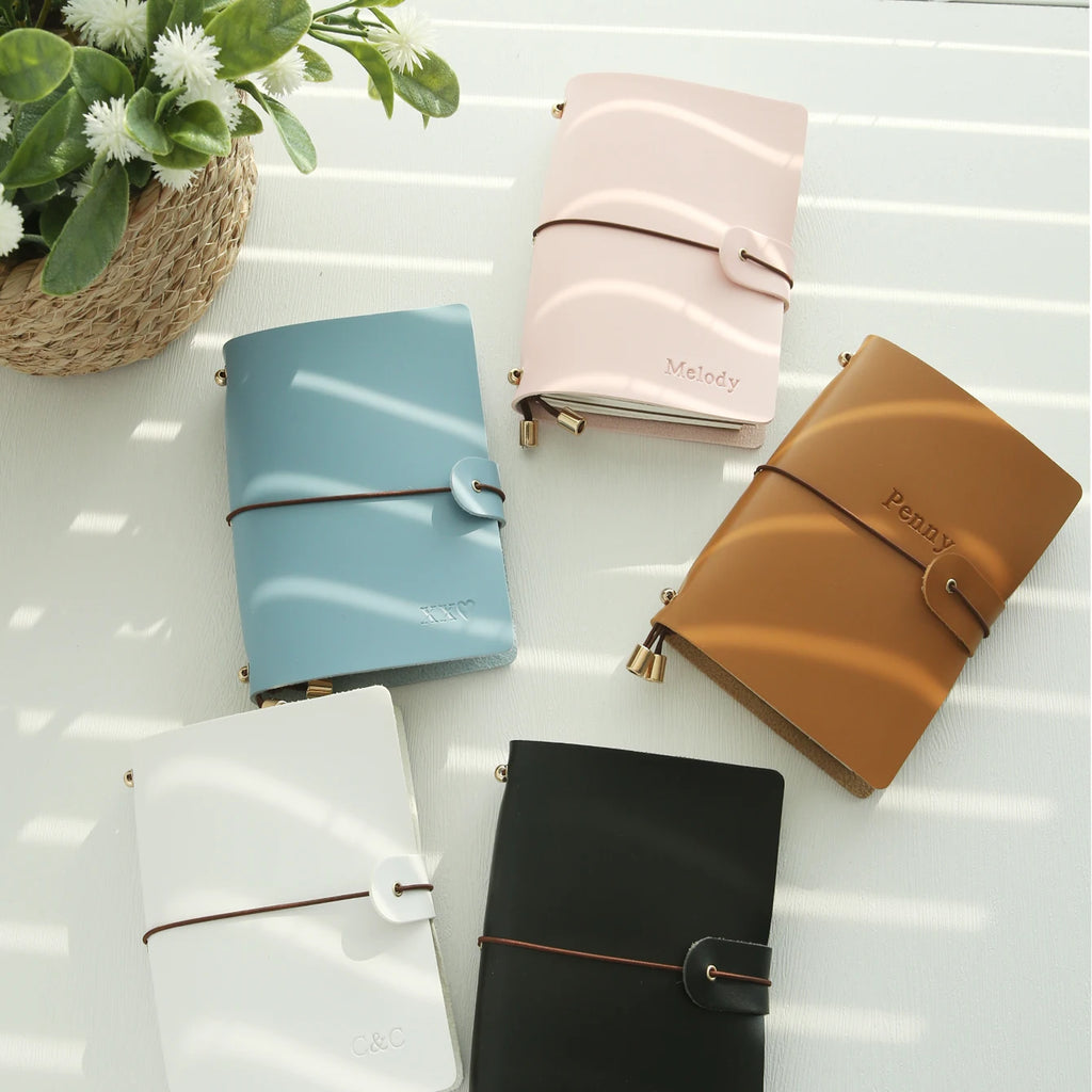 Vegan leather passport holder set in light blue, pink, tan, white, and black with snap straps