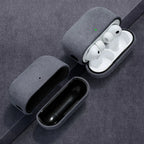 Opened gray Alcantara AirPods case with white AirPods seated; suede textured shell