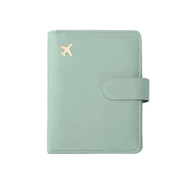 Mint green passport folio with gold airplane emblem and wrap-around strap closure