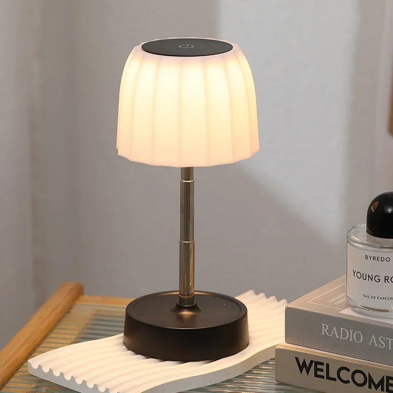 Warm LED desktop lamp with white pleated shade, black circular base, gold telescopic stem
