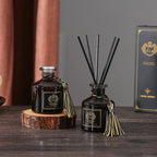 Reed diffuser bottles on wood slice, dark glass with black reeds and gold tassel ties