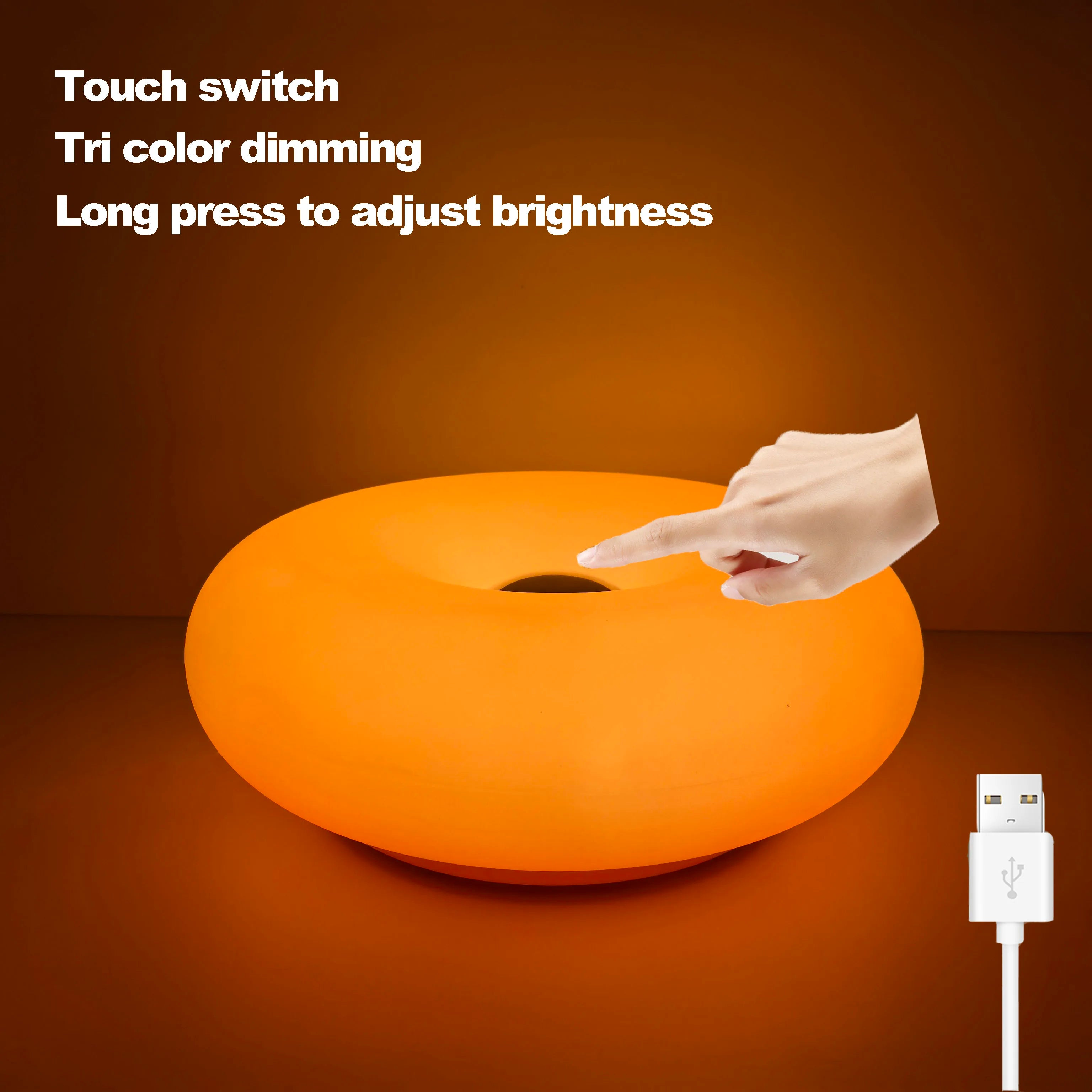 Orange glowing donut table lamp with USB charging cable connected.