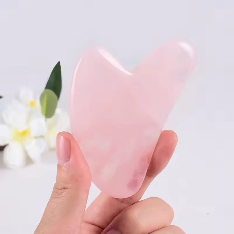 Rose quartz gua sha stone held upright, pointed end and smooth edge