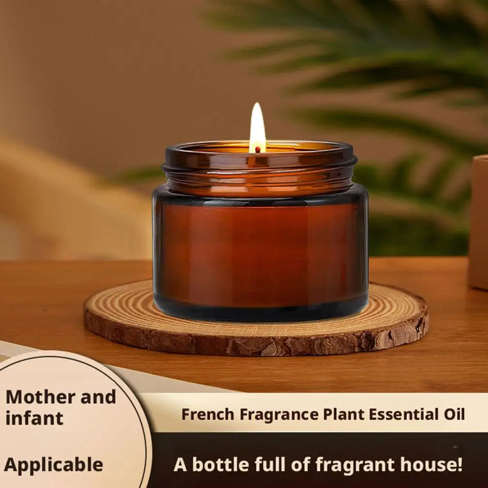 Amber scented candle in glass jar lit on a wooden coaster with flame visible