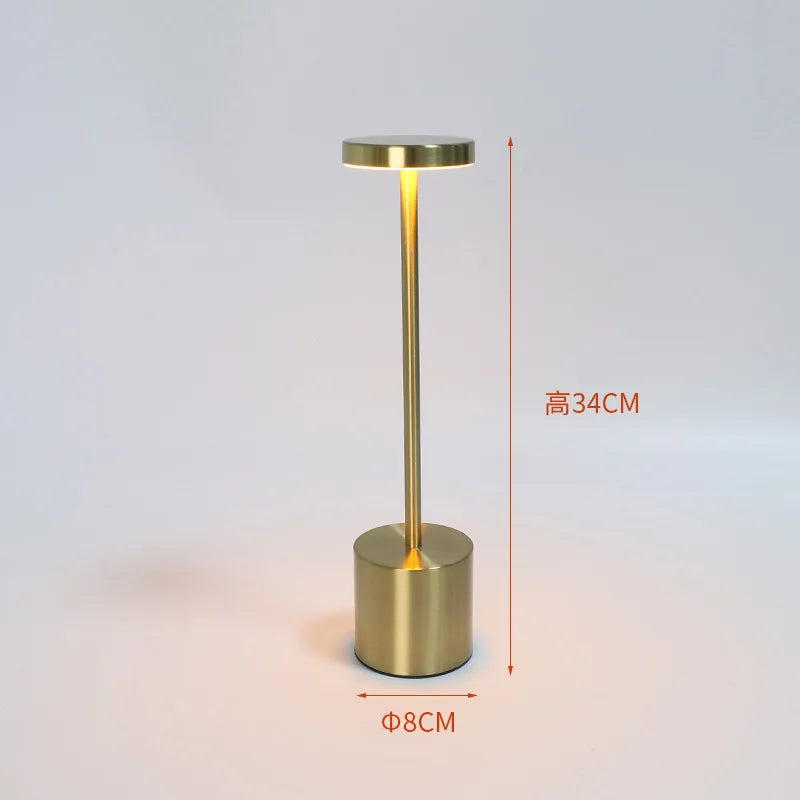 Gold table lamp with slim stem and cylindrical base; 34cm height, 8cm width
