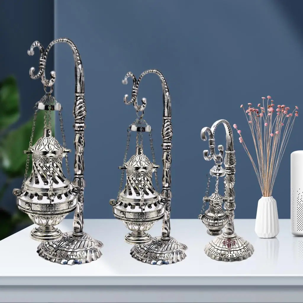 Close view of metal censer with ash catcher: arched spouts, chain-hung top ornament
