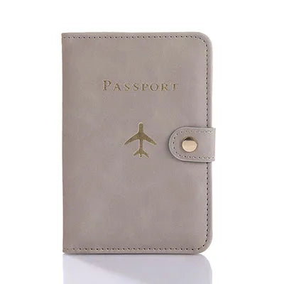 Light pink passport folio with gold airplane emblem and side strap tab