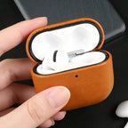 Warm brown eco leather AirPods case with earbuds inside, open lid and orange rim