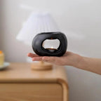 Black ceramic aroma oil burner held in hand, with window and lit candle