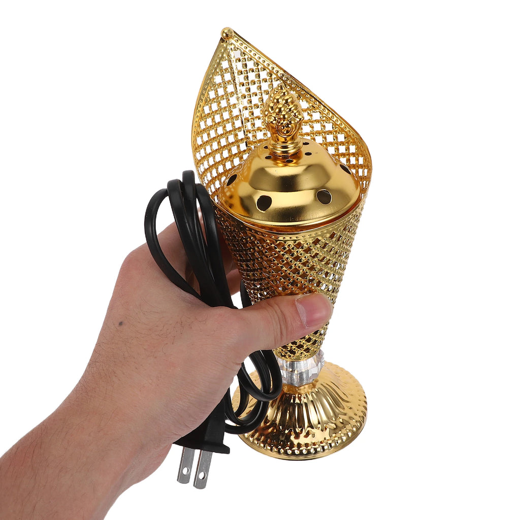 Gold electric mabkhara held in hand with black plug cord and base