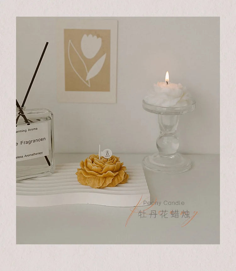 Yellow peony sculptural candle with lit wick on a pedestal
