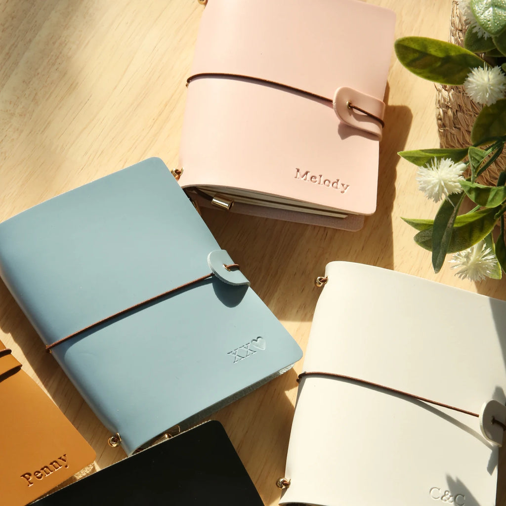 Pastel pink vegan leather passport holder with buckle strap and name engraving on front flap