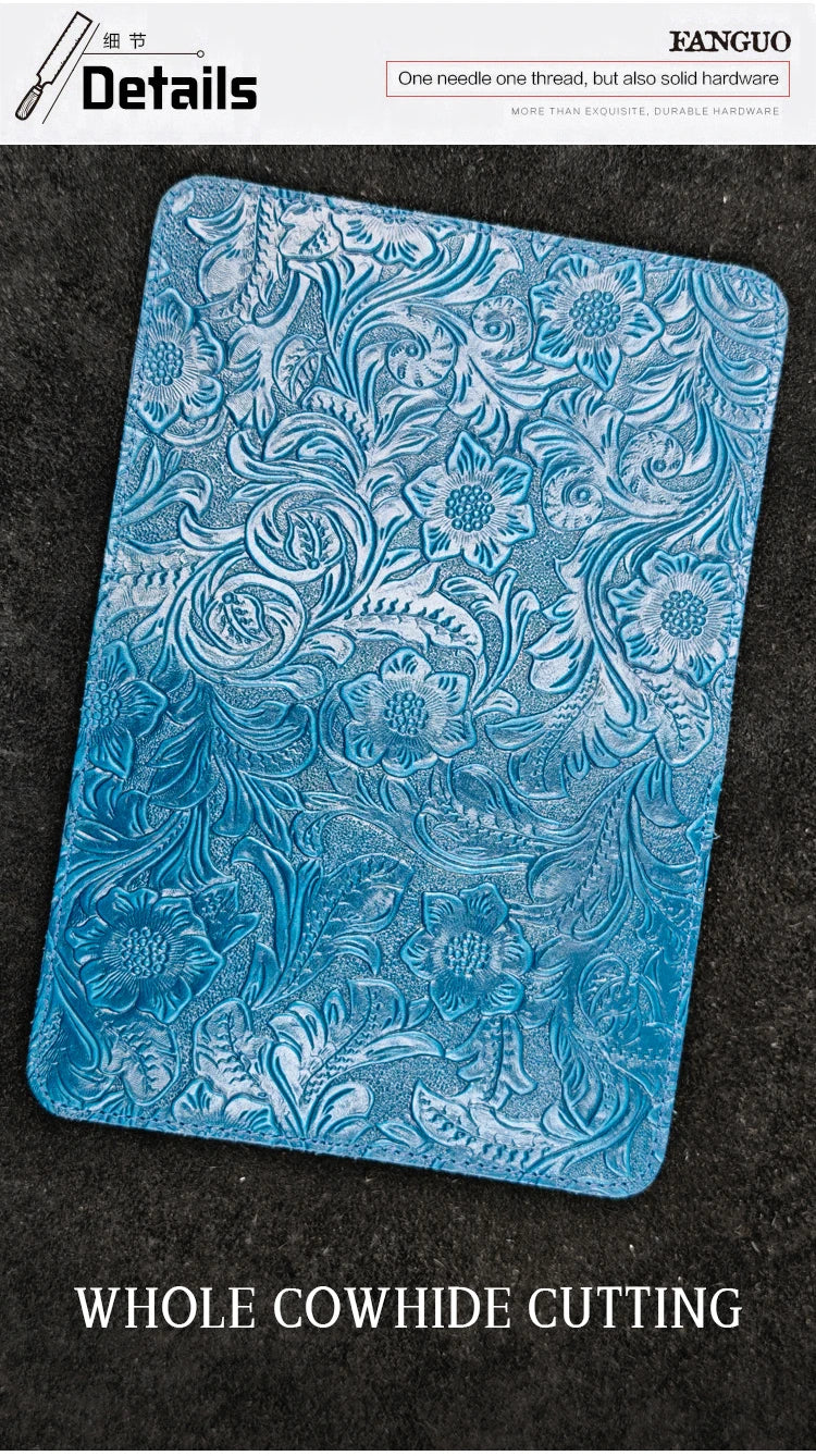 Blue embossed leather travel folio with detailed floral-and-vine pattern, flat view.
