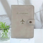 Blush pink passport cover with “PASSPORT” text, airplane emblem, and side snap strap