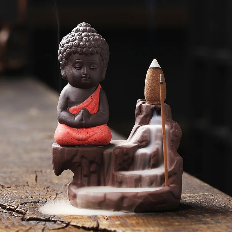 Backflow incense burner with seated Buddha figure, red robe, incense cone on base