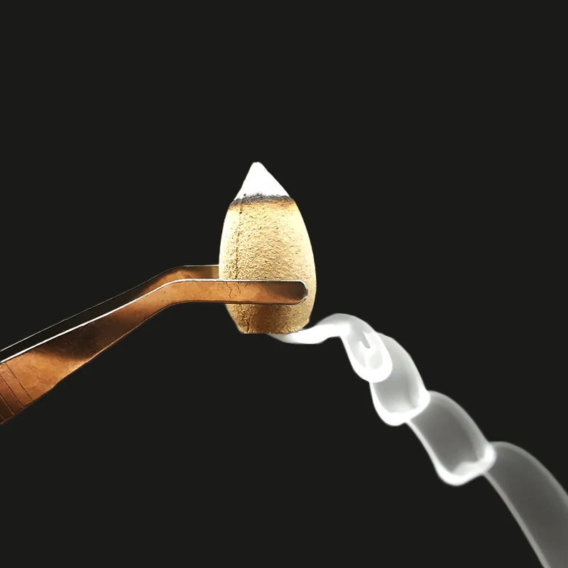 Single golden backflow incense cone on a brass holder with rising smoke