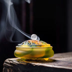 Amber glass incense vessel with ornate lid, glowing top and smoke