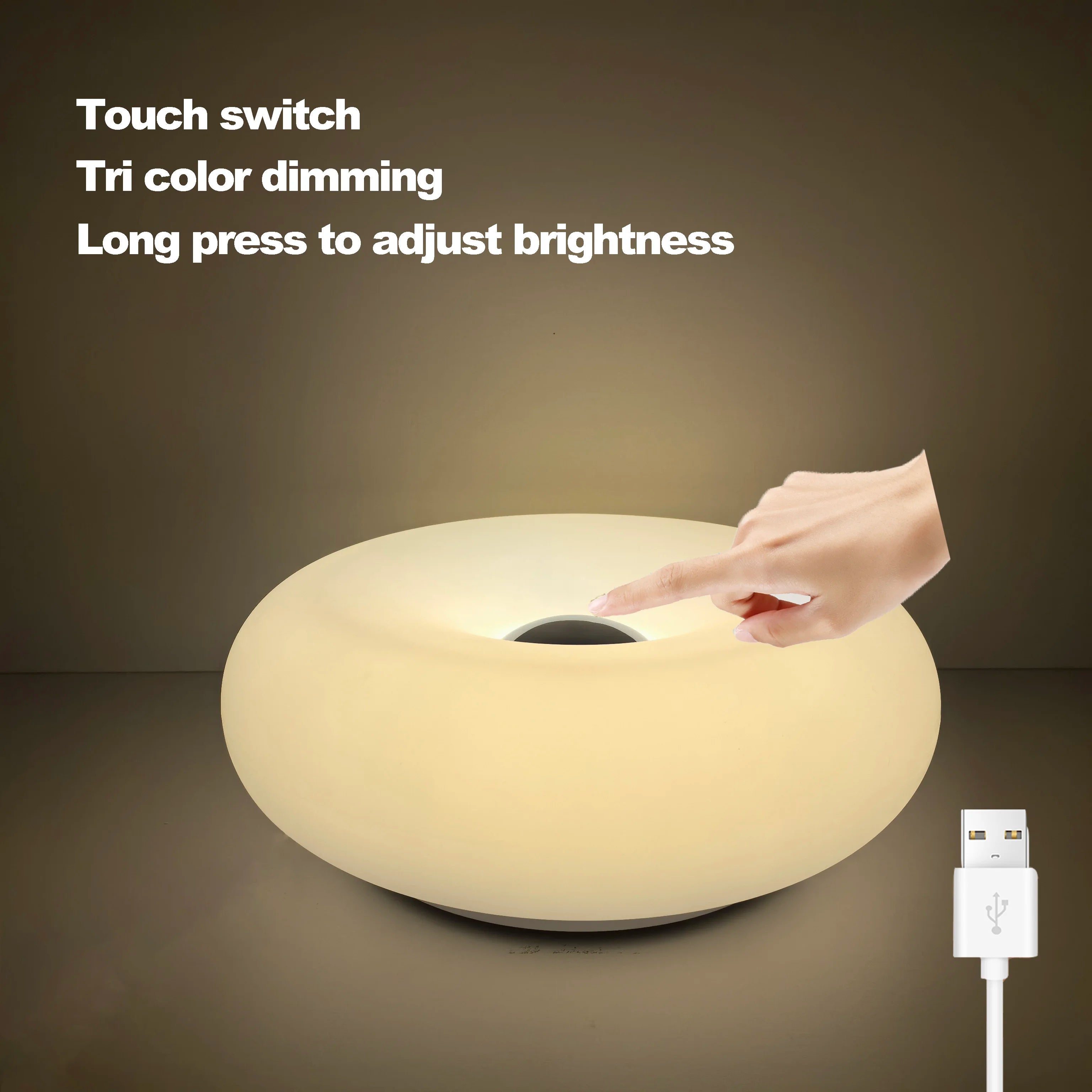 White donut table lamp with touch control, hand on top and USB charging cable.