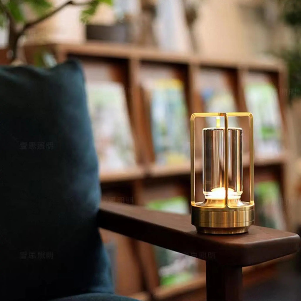 Gold cordless reading lamp on a desk with glass lantern sides and glowing core