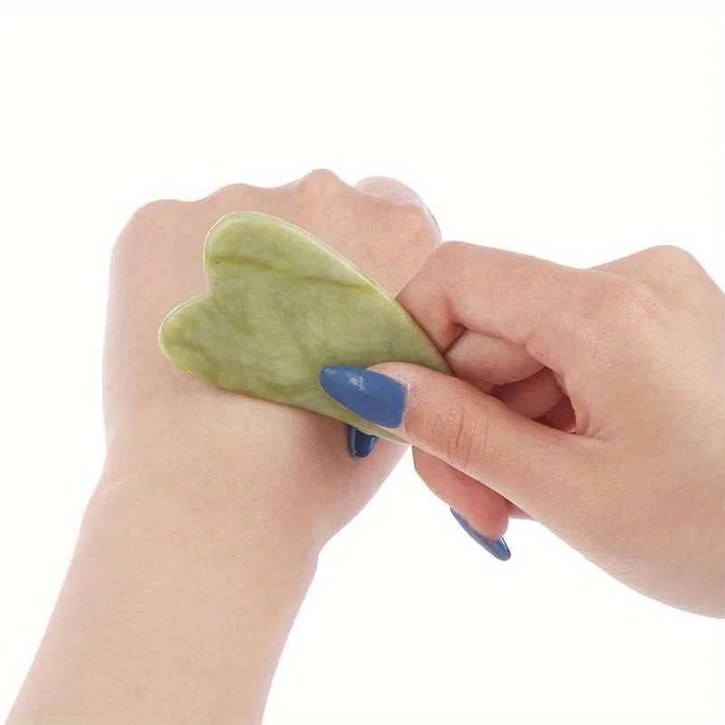 Classic Jade gua sha stone held in hand, oval edge for facial massage