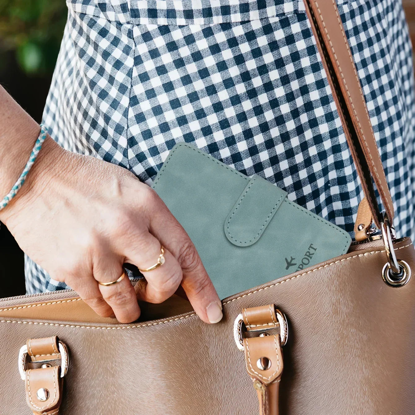Sage green passport wallet with front flap tucked in a tote bag