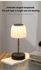 Cordless LED lamp with umbrella-shaped white shade on metal stem and round base