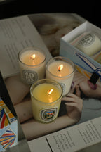 Three French Botanical scented candles lit inside clear glass jars