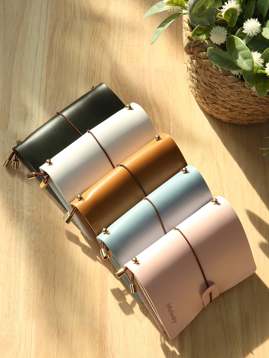Vegan leather passport holders in dark black, white, tan, and pastel blue with metal clasps