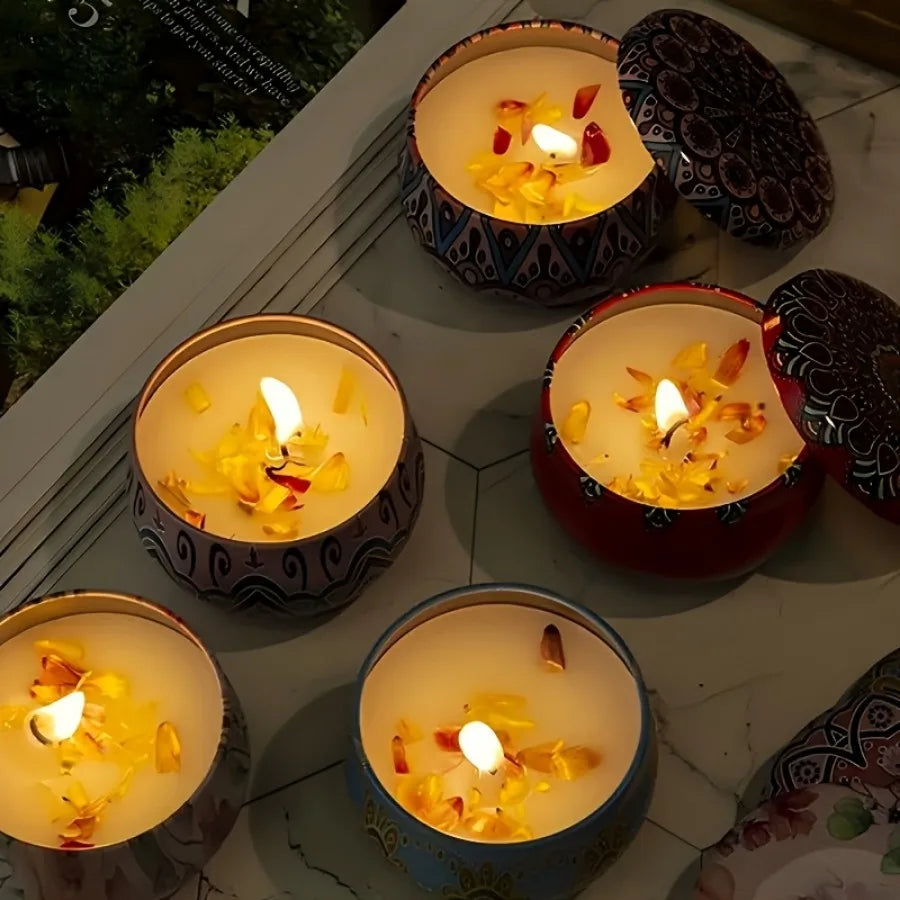 Multiple patterned scented candle jars with lit flames in colorful round tins