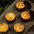 Multiple patterned scented candle jars with lit flames in colorful round tins