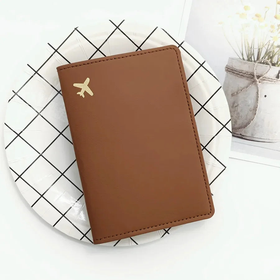 Warm espresso passport sleeve with gold plane emblem and stitched border