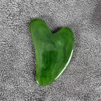 Green gua sha stone with smooth heart shape and glossy polished surface