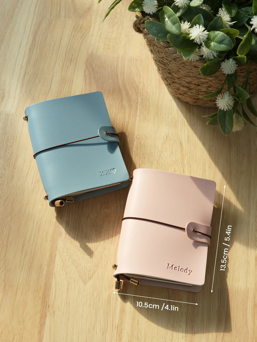 Light blue and pastel pink vegan leather passport holders with buckle straps and gold corner clips