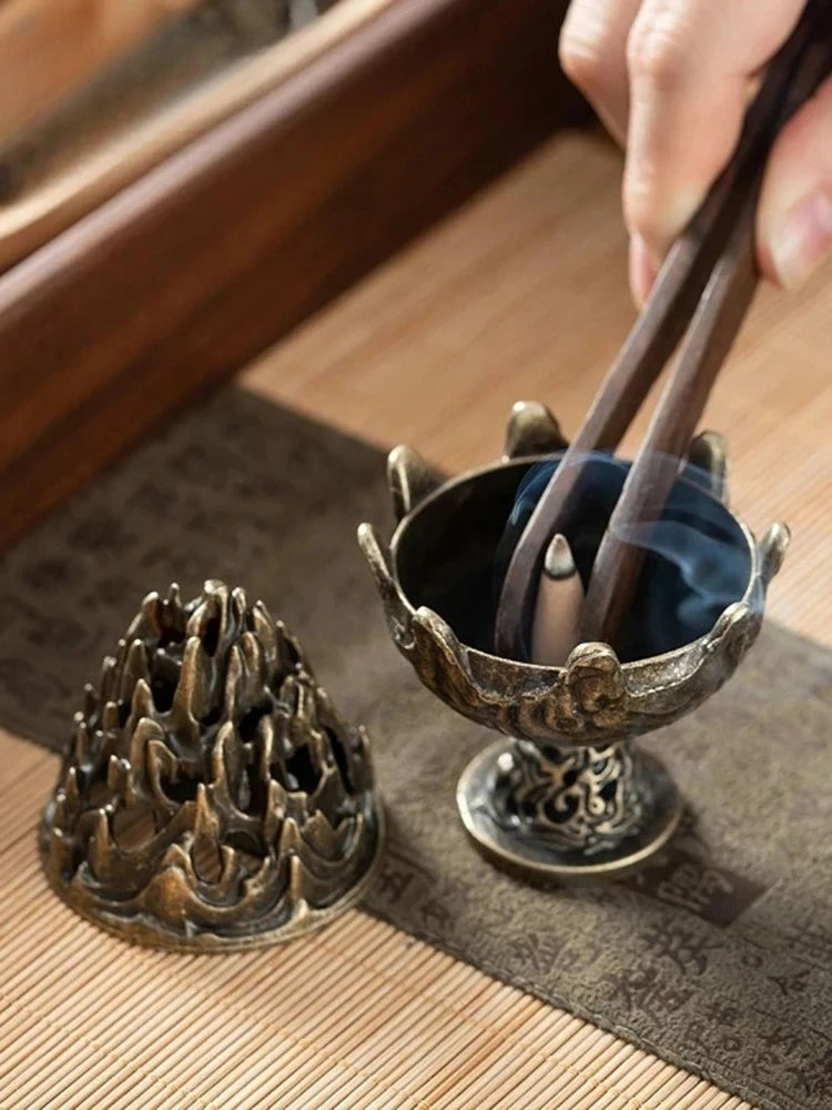 Copper incense censer and another burner on tabletop, both with smoke streams