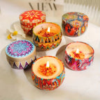 Assorted patterned scented candles with lit flames in colorful round containers