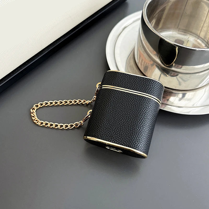 Obsidian dark wrist strap AirPods case with gold chain and bottom cutouts.