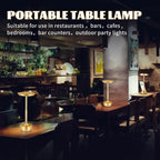 Golden portable table lamp with tall stem and round base on restaurant table