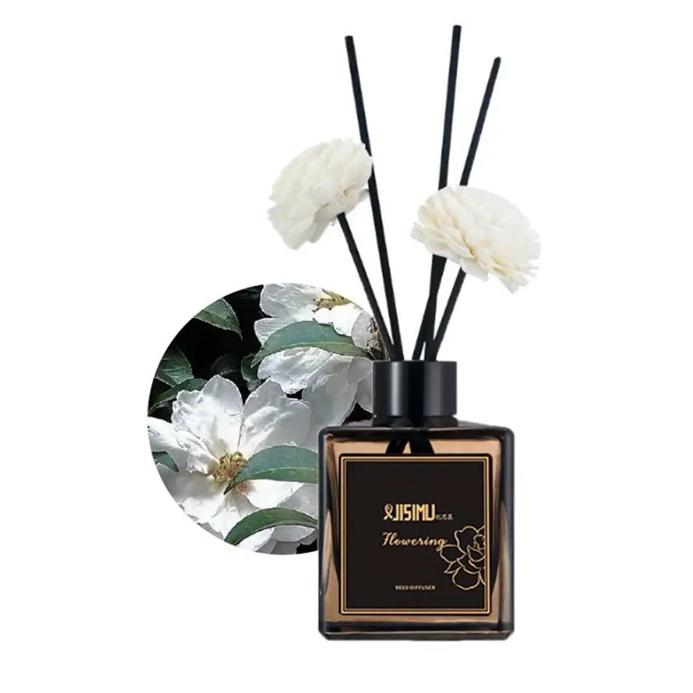 Reed diffuser set with white flower-tipped reeds and black bottle on green botanical circle