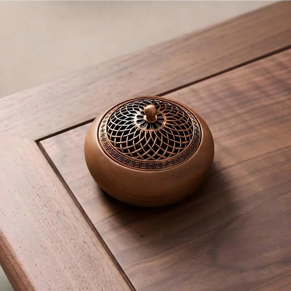 Round solid wood incense tray on square surface with ornate metal lid and knob