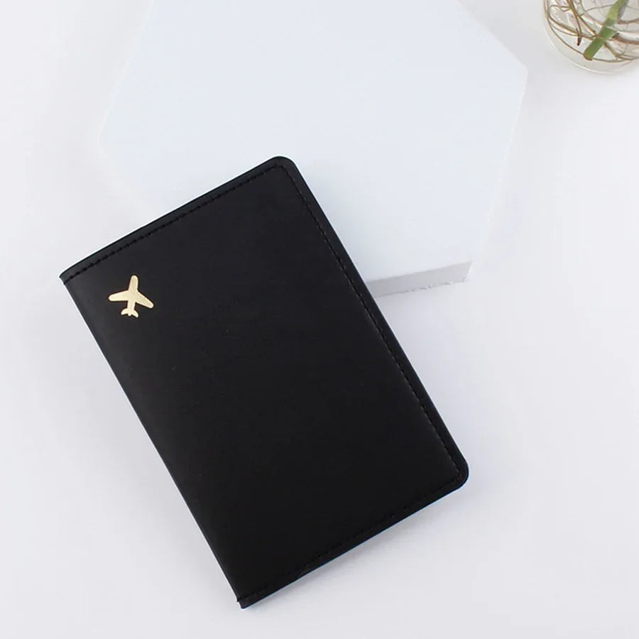 Midnight black passport sleeve with gold plane emblem and stitched border
